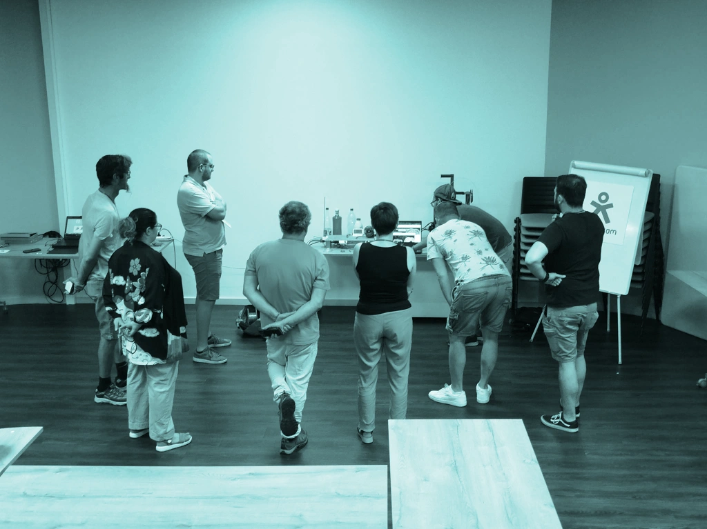 Participants à l'ExplorCamp des Espaces du Faire de la Loire, de dos, examinant la table du projet de la Ville de Saint-Étienne.